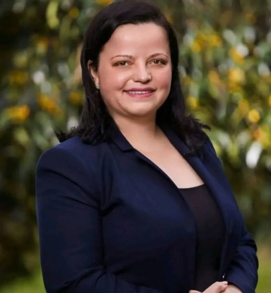 Portrait of Amira Hamit wearing a navy blazer, smiling confidently.