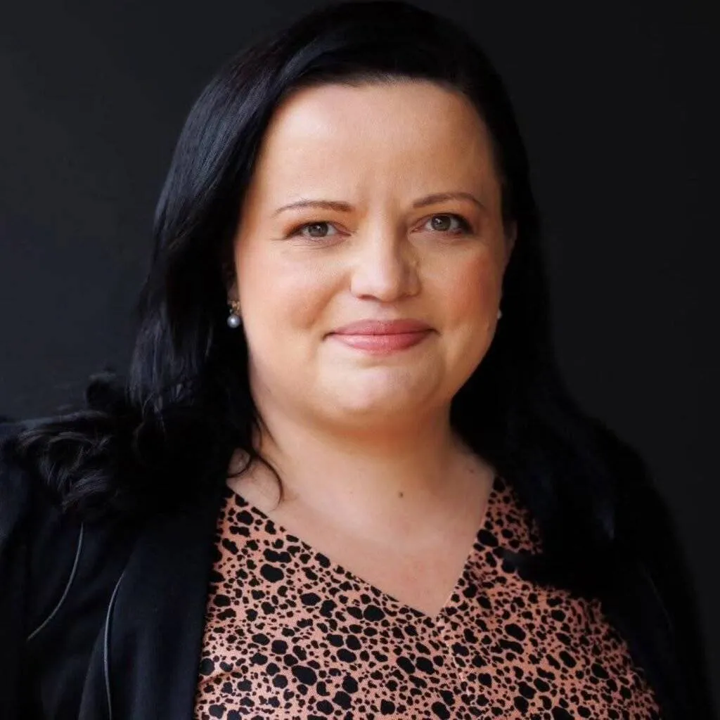 Amira Hamit headshot. Professional woman with dark hair in patterned top and black jacket.